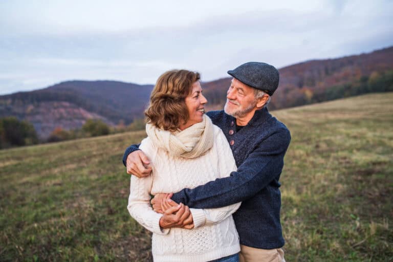 Happy couple embracing in a field, representing financial security and homeownership for UK buyers.