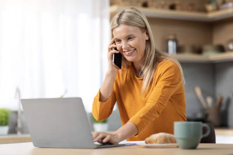 Woman on phone discussing mortgage options and financial advice with laptop and home setting.